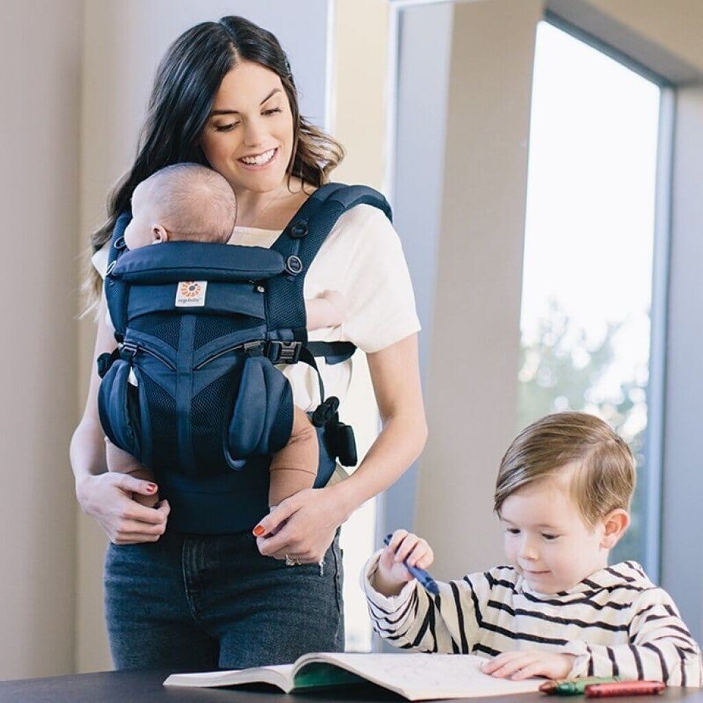 bebe dans porte bebe maman regarde petit frere dessine